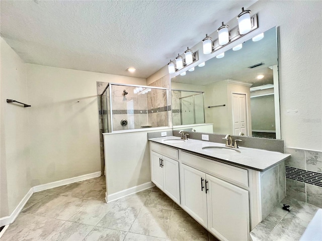 bathroom with visible vents, a stall shower, a textured ceiling, and a sink