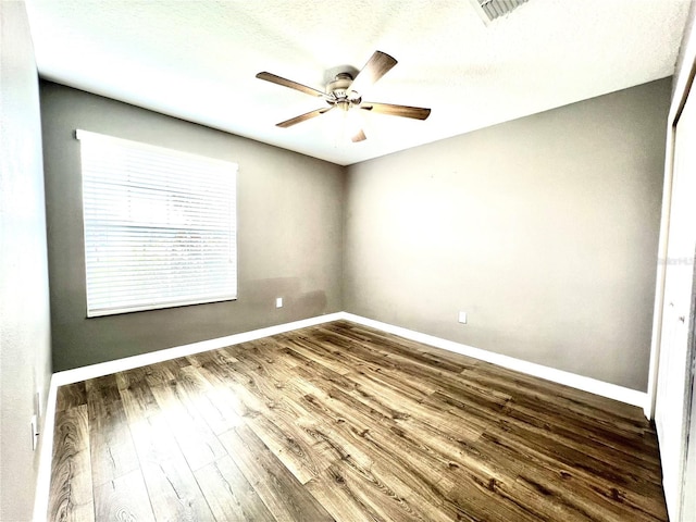 unfurnished room with a ceiling fan, wood finished floors, visible vents, baseboards, and a textured ceiling