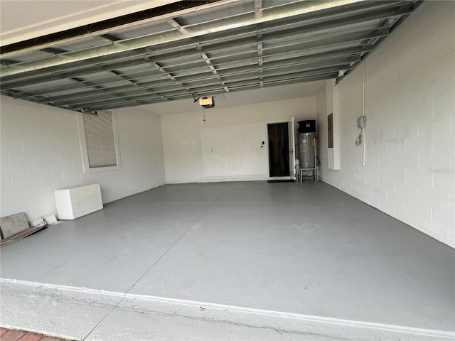 garage featuring electric panel, concrete block wall, a garage door opener, and water heater