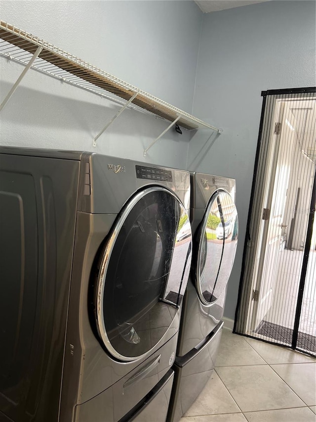 clothes washing area featuring light tile patterned floors, laundry area, and washing machine and dryer