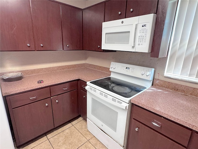 kitchen with light tile patterned floors, white appliances, and light countertops