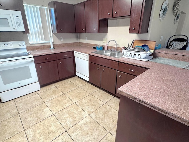 kitchen with white appliances, light tile patterned floors, dark brown cabinetry, and a sink