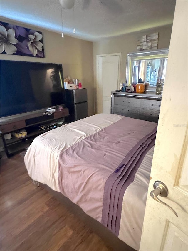 bedroom featuring wood finished floors and freestanding refrigerator