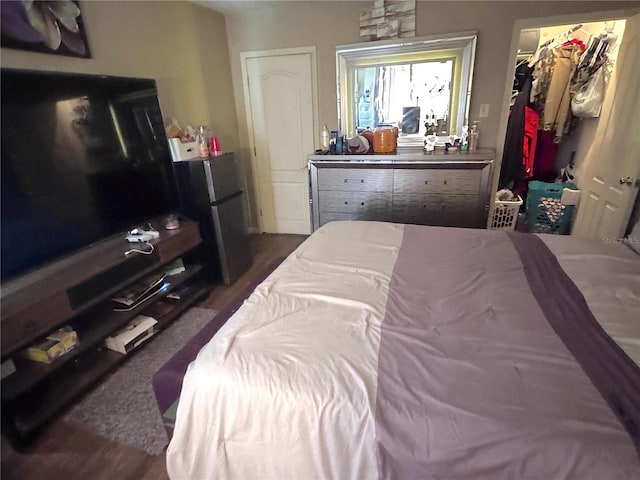 bedroom with a spacious closet, freestanding refrigerator, and a closet