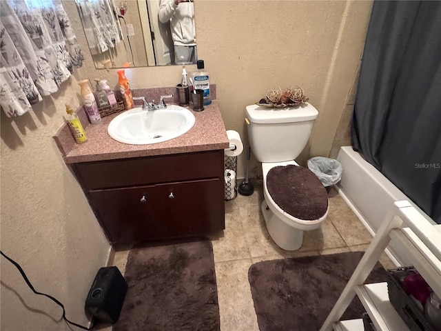 bathroom with toilet, vanity, shower / tub combo, and a textured wall