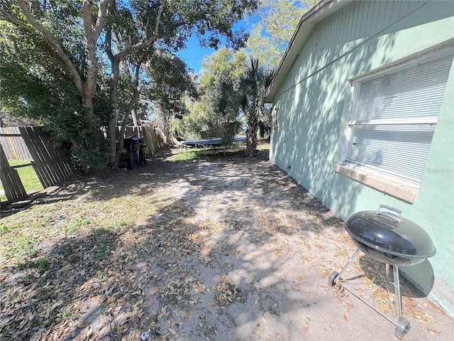 view of yard featuring a trampoline and fence