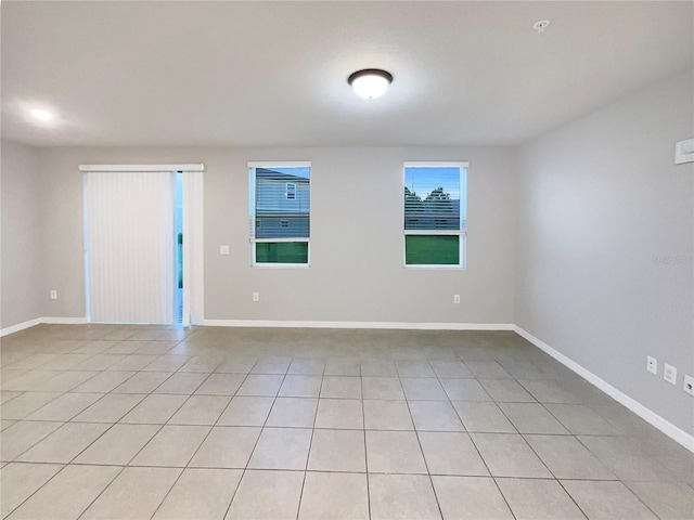 empty room with light tile patterned flooring and baseboards