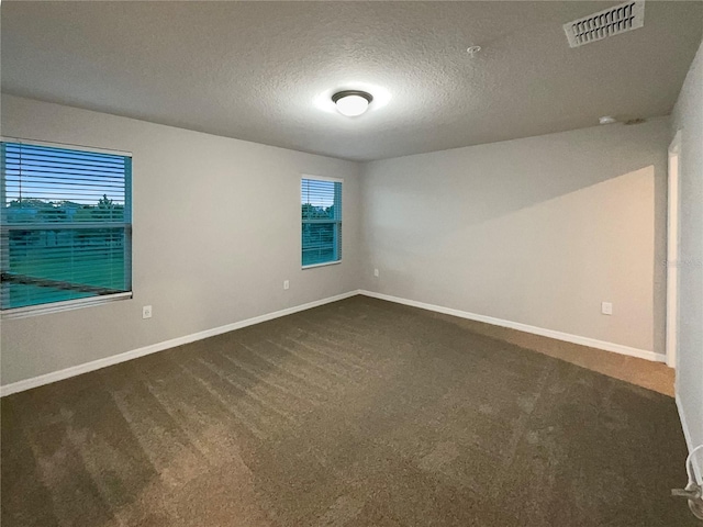 unfurnished room featuring visible vents, baseboards, and dark colored carpet