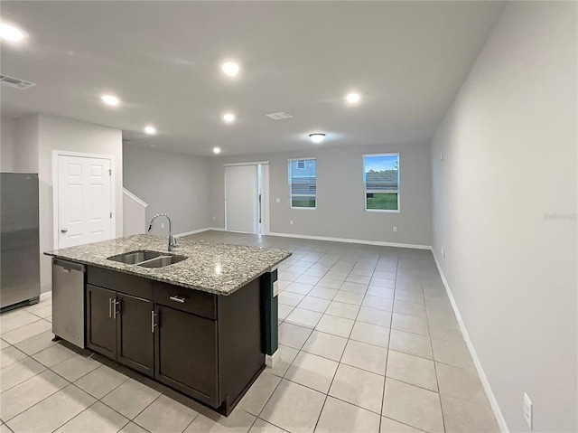 kitchen featuring light tile patterned floors, visible vents, an island with sink, a sink, and stainless steel appliances