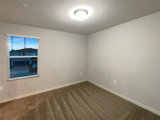 empty room featuring dark colored carpet, baseboards, and a textured ceiling