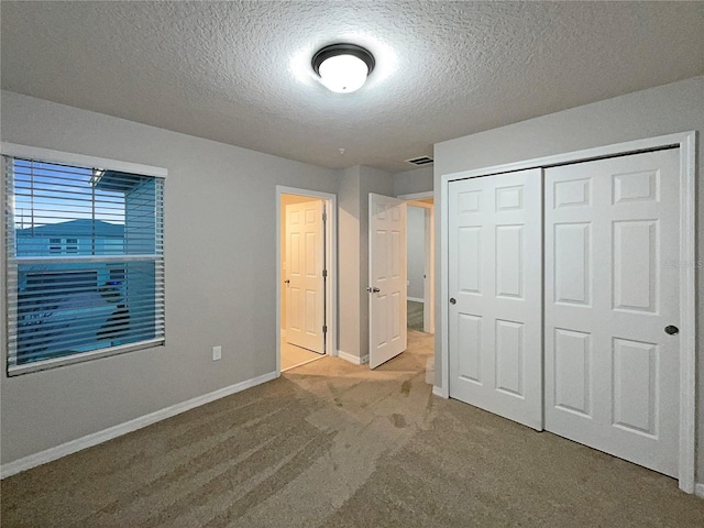 unfurnished bedroom featuring visible vents, baseboards, carpet floors, a closet, and a textured ceiling