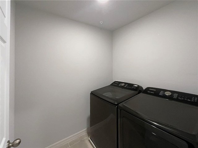 washroom with light tile patterned flooring, laundry area, washing machine and dryer, and baseboards