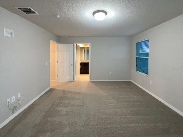 unfurnished room with a textured ceiling, carpet, visible vents, and baseboards