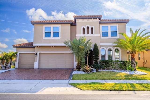 mediterranean / spanish house with stucco siding, decorative driveway, a front lawn, and a tile roof