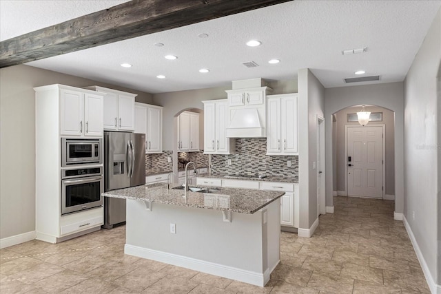 kitchen with arched walkways, visible vents, appliances with stainless steel finishes, and a sink