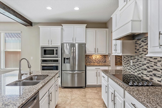 kitchen featuring tasteful backsplash, custom range hood, appliances with stainless steel finishes, white cabinets, and a sink