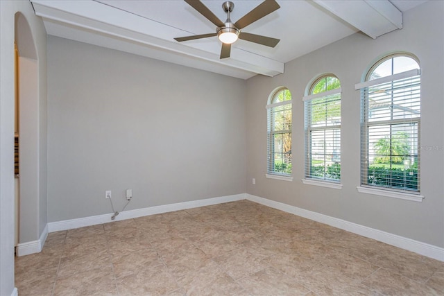 empty room featuring arched walkways, beamed ceiling, a ceiling fan, and baseboards