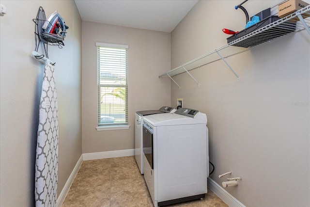 clothes washing area with laundry area, washing machine and dryer, and baseboards