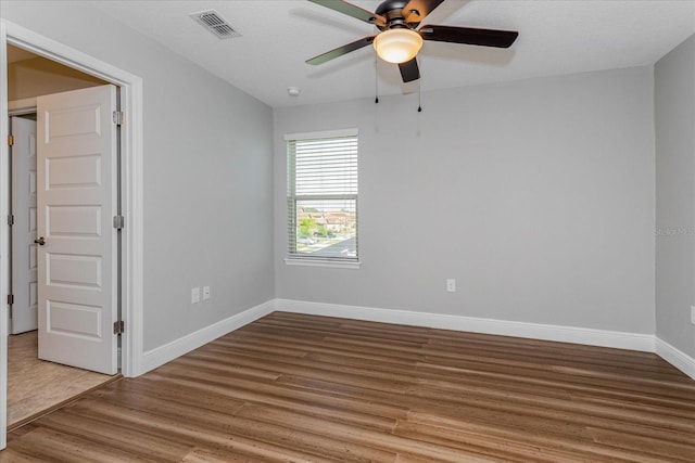 spare room featuring visible vents, ceiling fan, baseboards, and wood finished floors