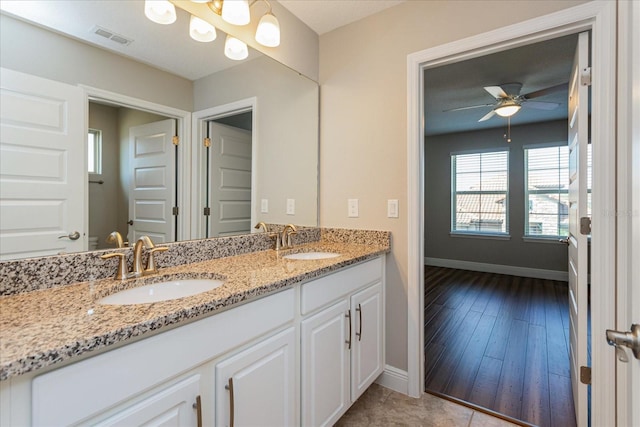 bathroom featuring double vanity, visible vents, baseboards, and a sink