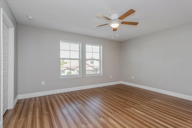 unfurnished room with light wood-type flooring, baseboards, and a ceiling fan