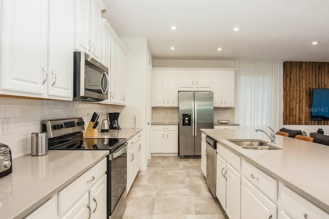 kitchen featuring a sink, tasteful backsplash, white cabinetry, appliances with stainless steel finishes, and light countertops