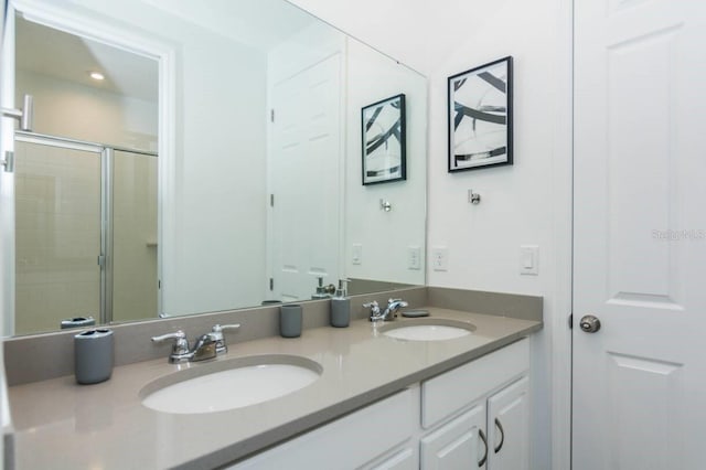 bathroom with double vanity, a shower stall, and a sink