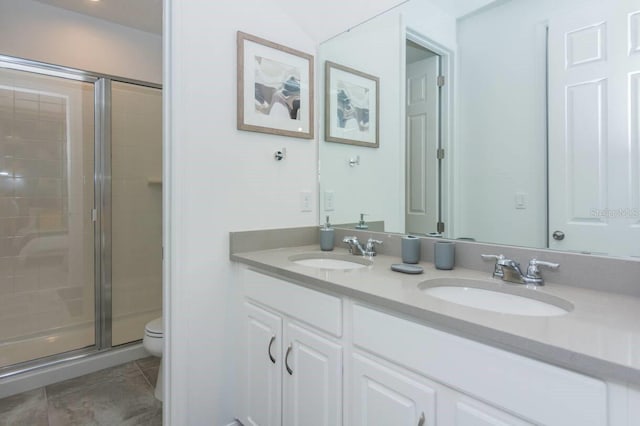 bathroom with a sink, toilet, double vanity, and a shower stall