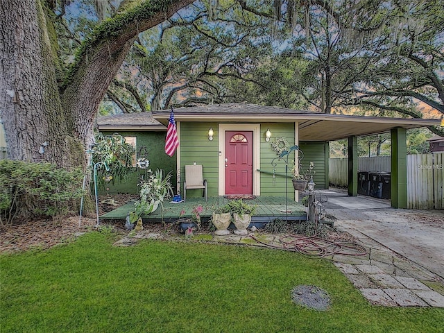 view of front of property featuring a carport, concrete driveway, a front yard, and fence