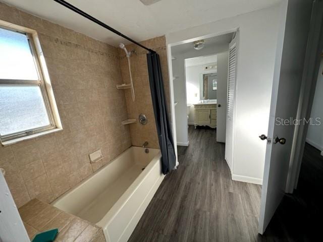 full bath featuring shower / bath combo with shower curtain, baseboards, and wood finished floors