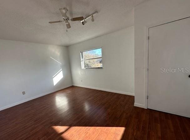 spare room featuring baseboards, a textured ceiling, and wood finished floors