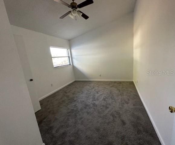 carpeted spare room featuring lofted ceiling, baseboards, and ceiling fan