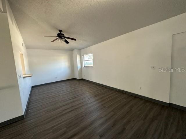 unfurnished room featuring ceiling fan, baseboards, a textured ceiling, and dark wood finished floors