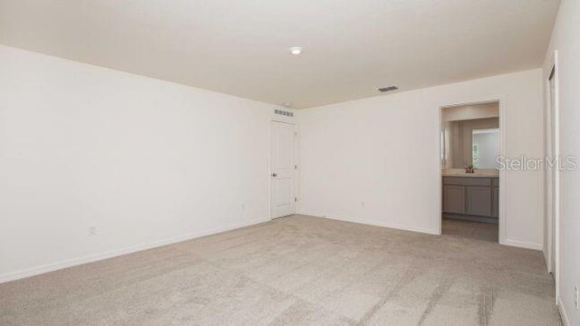 empty room with visible vents, light colored carpet, and baseboards