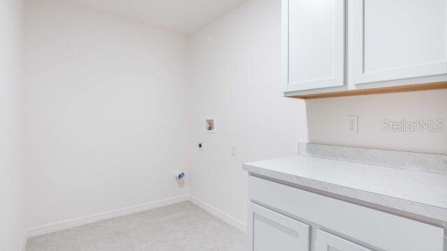 washroom featuring electric dryer hookup, baseboards, washer hookup, and cabinet space