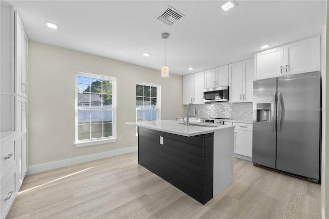 kitchen with visible vents, a sink, appliances with stainless steel finishes, white cabinetry, and tasteful backsplash