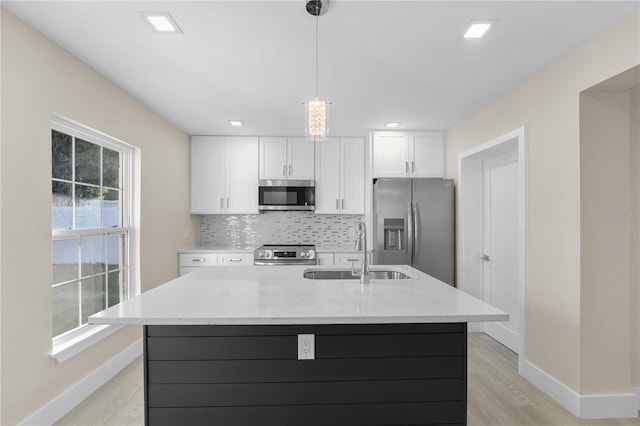 kitchen featuring tasteful backsplash, white cabinetry, stainless steel appliances, and a sink