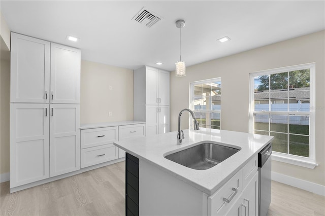 kitchen featuring visible vents, a sink, hanging light fixtures, white cabinets, and stainless steel dishwasher