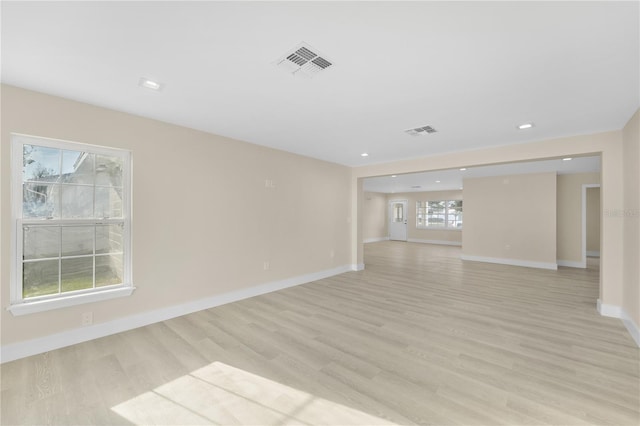 empty room with visible vents, light wood-style floors, and baseboards