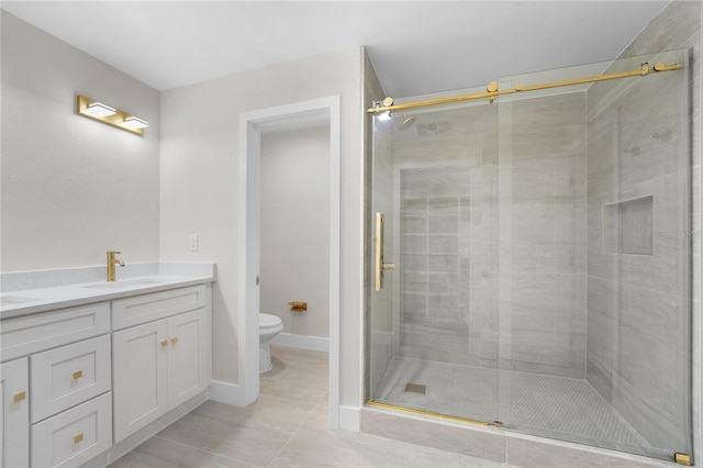 bathroom with double vanity, a sink, tile patterned flooring, a shower stall, and toilet