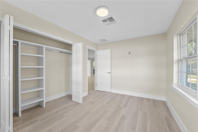 unfurnished bedroom featuring visible vents, baseboards, light wood-style floors, and a closet