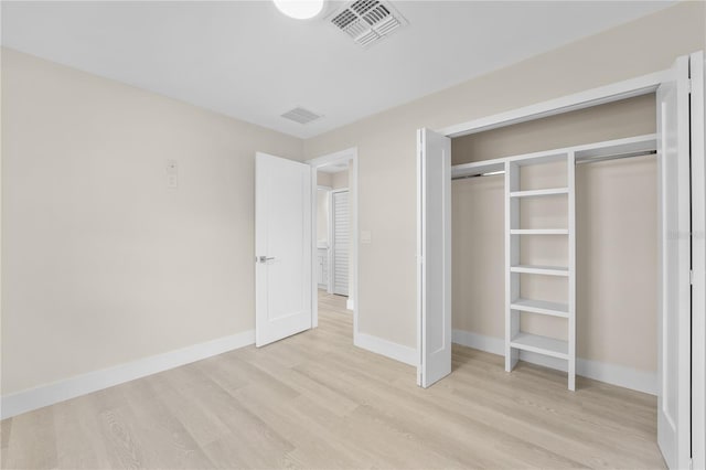 unfurnished bedroom featuring light wood-style floors, visible vents, a closet, and baseboards