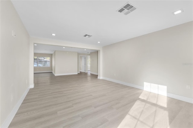 spare room featuring light wood finished floors, visible vents, and baseboards