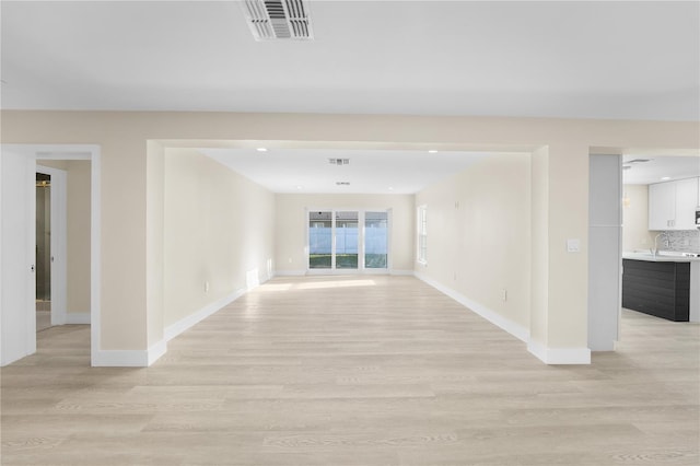 unfurnished room with light wood finished floors, visible vents, and baseboards