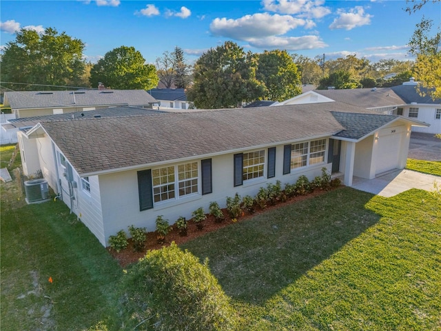 ranch-style house with central AC unit, roof with shingles, an attached garage, a front lawn, and concrete driveway