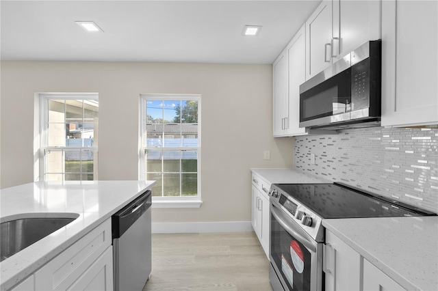 2418 Whitehall Cir, Winter Park, FL 32792 - kitchen with white cabinetry, light stone countertops, decorative backsplash, and appliances with stainless steel finishes