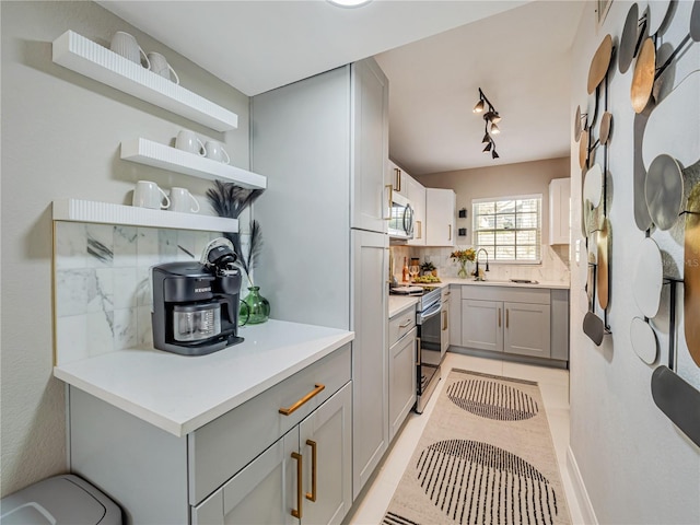 1174 Villa Ln Unit 115, Apopka, FL 32712 - kitchen with gray cabinetry, appliances with stainless steel finishes, open shelves, and tasteful backsplash