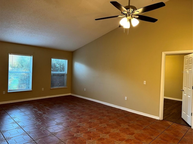 empty room with high vaulted ceiling, dark tile patterned flooring, a ceiling fan, a textured ceiling, and baseboards