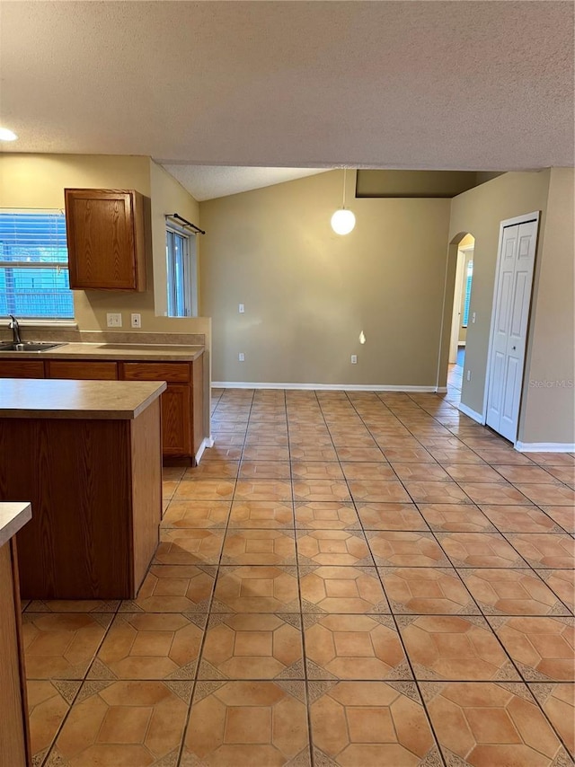 kitchen featuring light tile patterned floors, arched walkways, a textured ceiling, and a sink