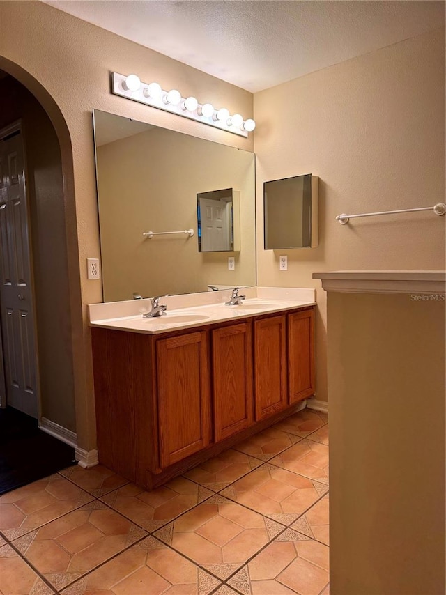 bathroom featuring double vanity, tile patterned floors, a textured ceiling, and a sink